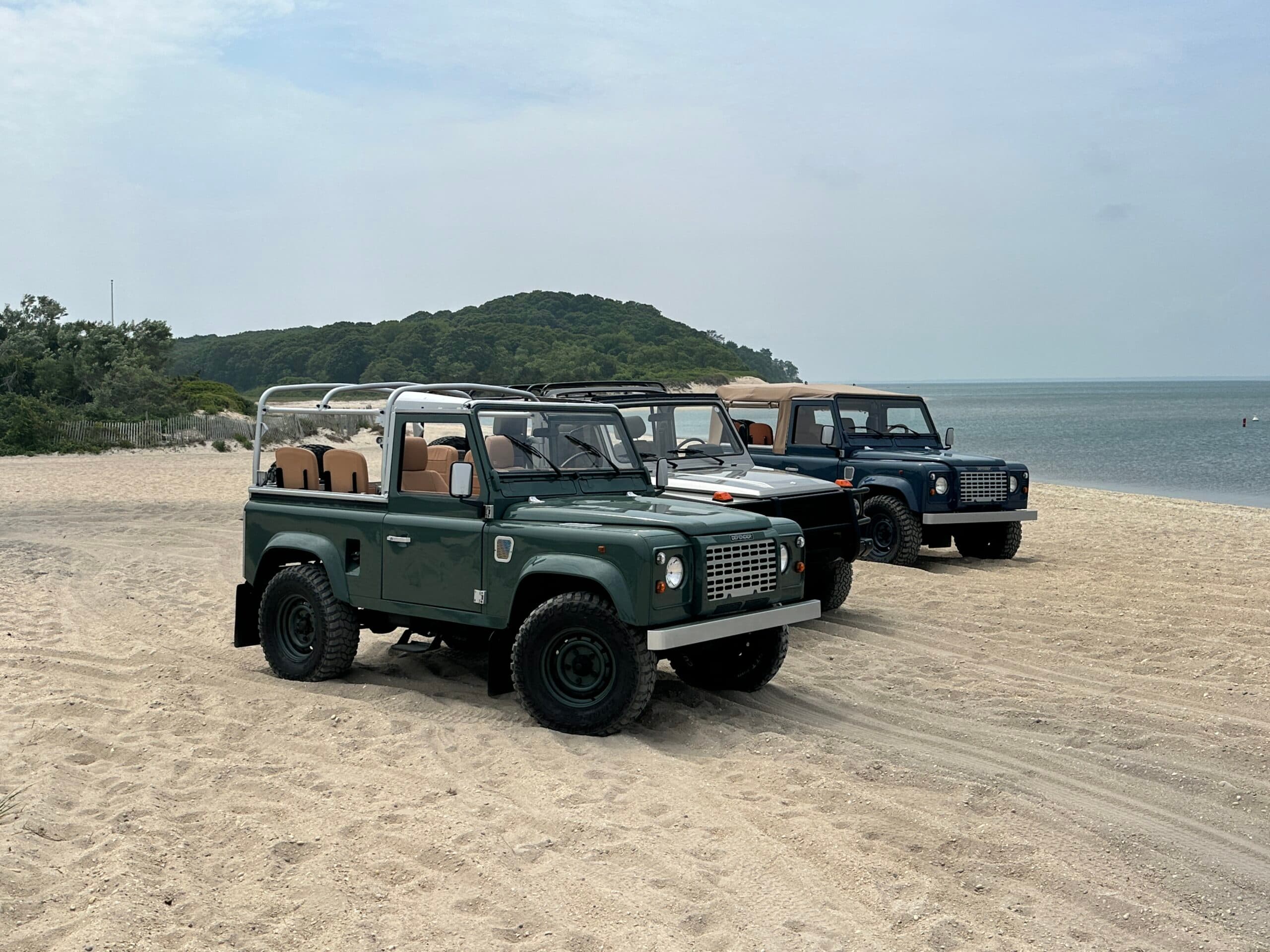 Classic Land Rover Defenders on a beach